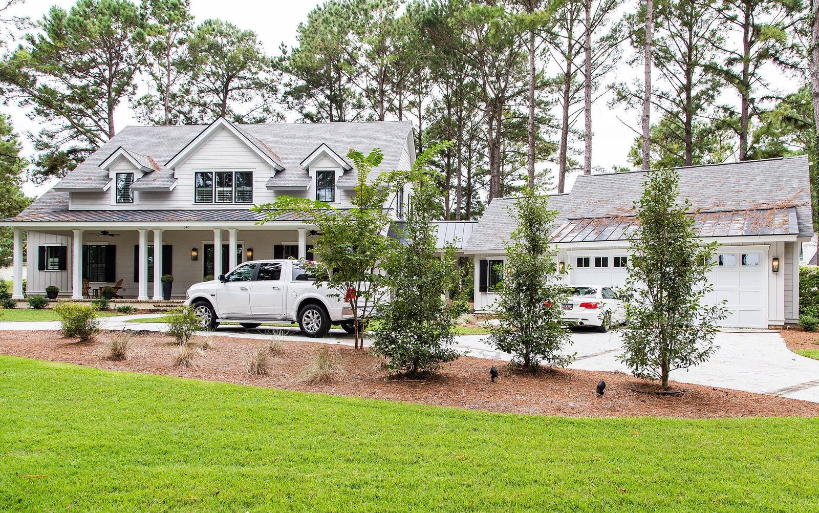 Lowcountry farmhouse seen from the drive with a wraparound porch and detached garage