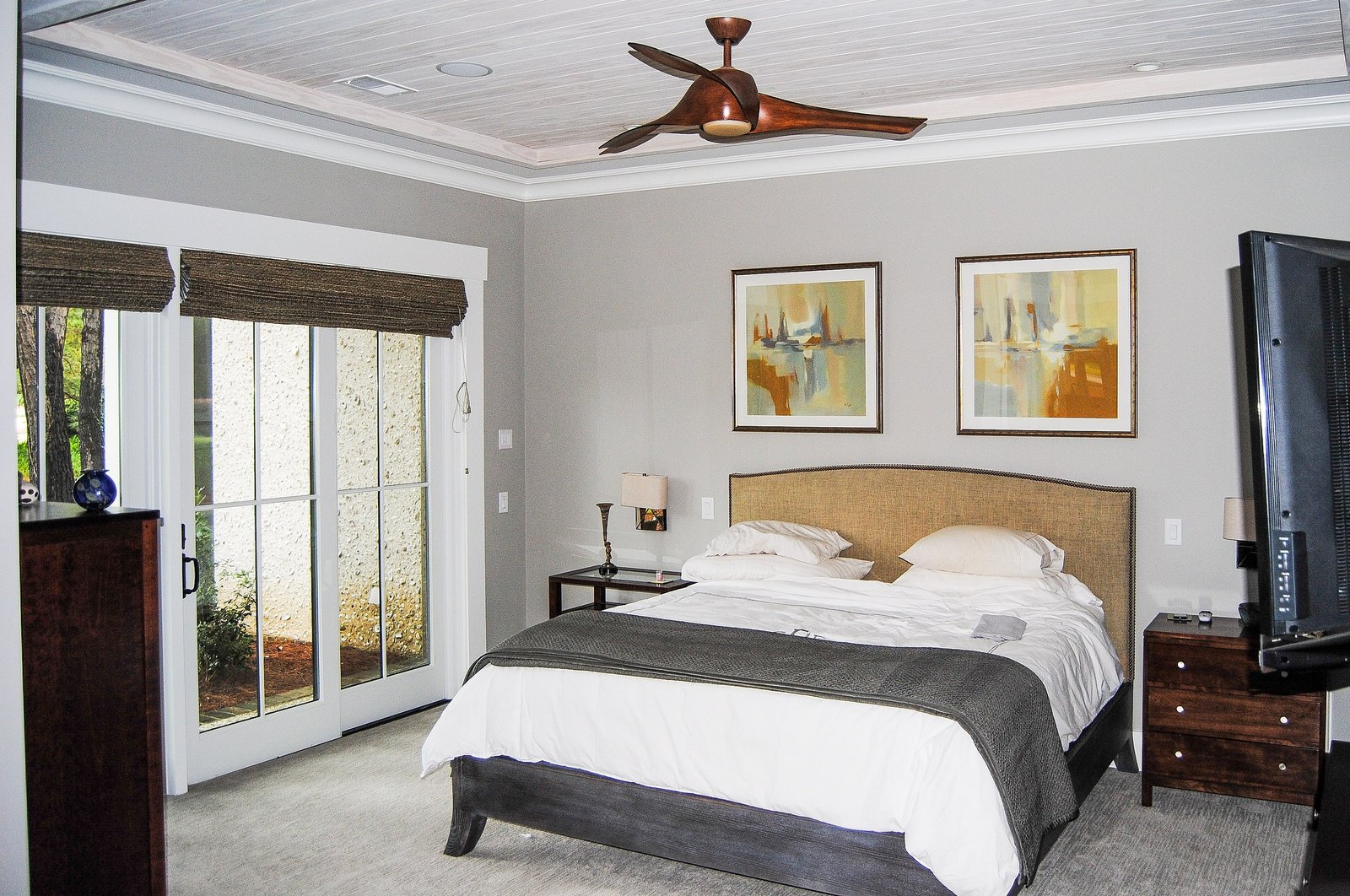 Master bedroom with a tray ceiling, upholstered bed and framed art