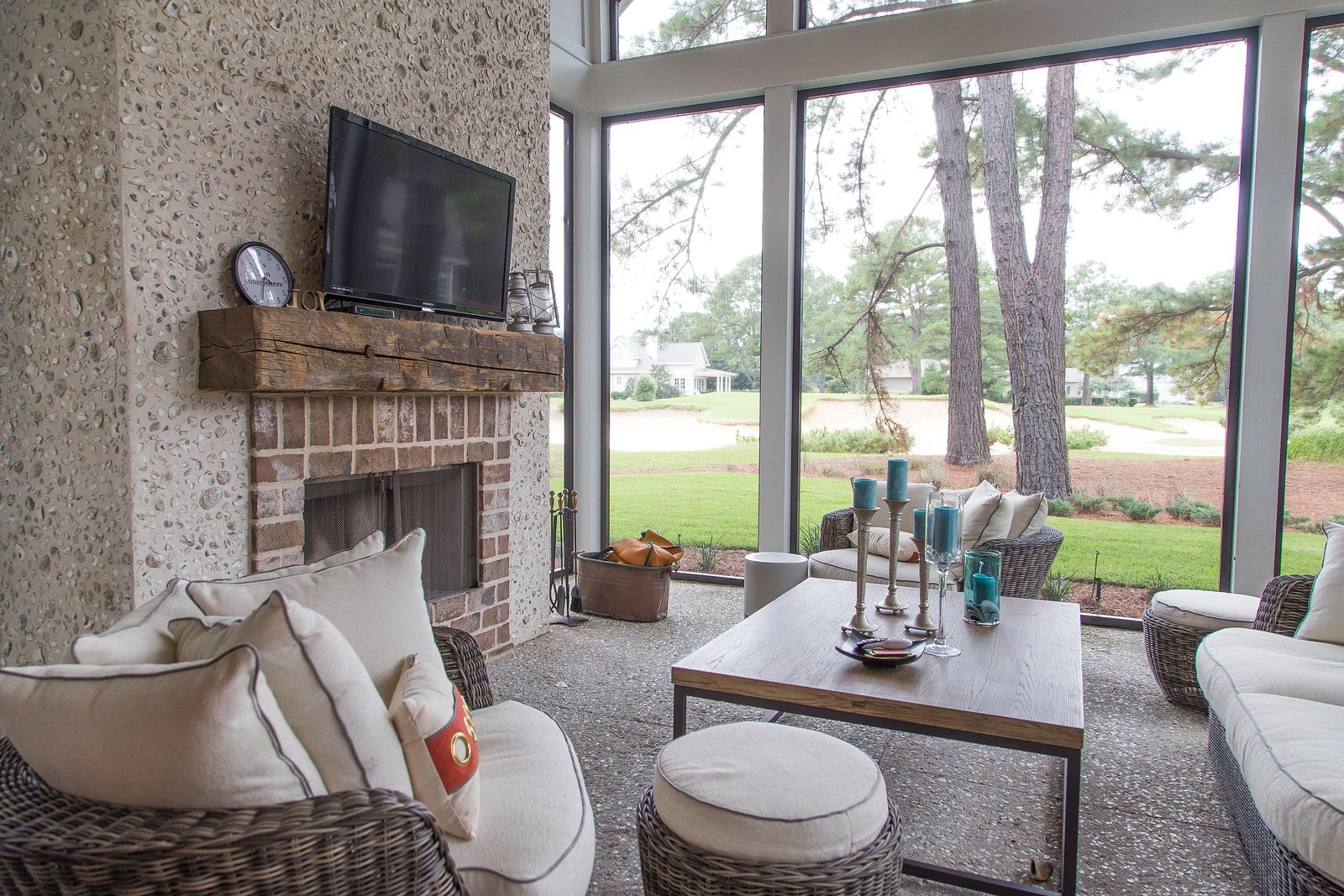 Screened porch with a stone fireplace, comfortable seating and fairway views