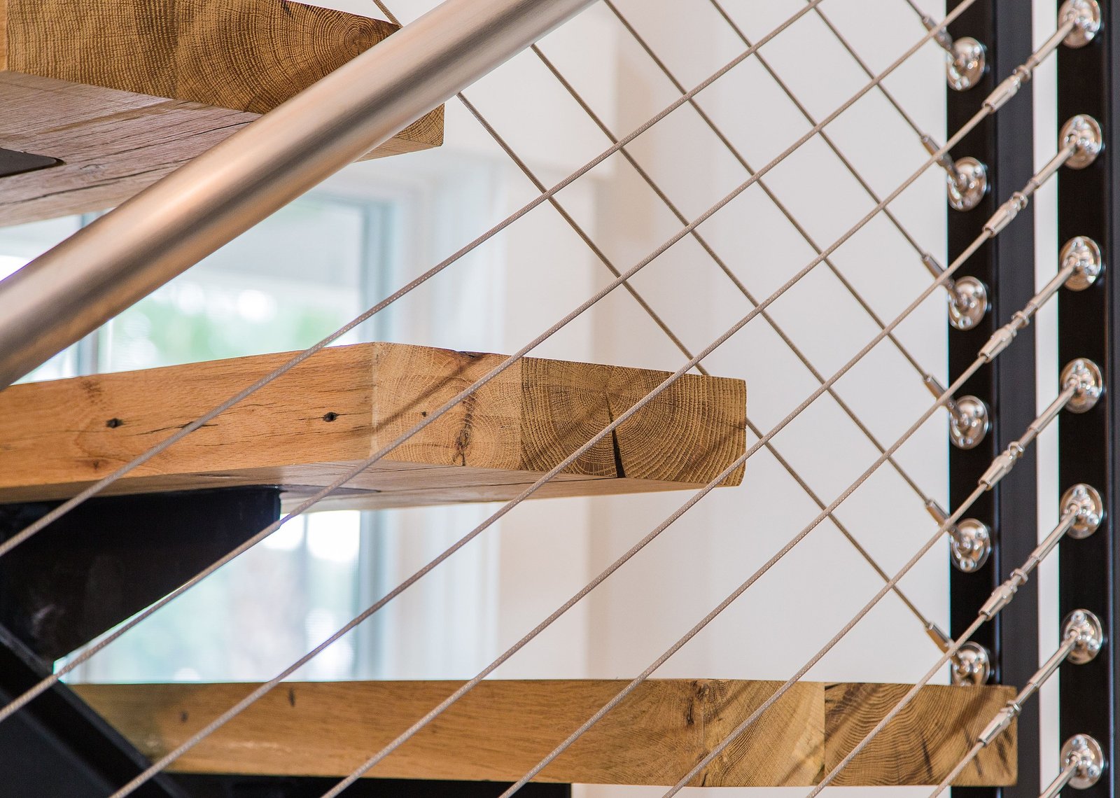 Close detail of the stair treads, cable railing and warm wood grain