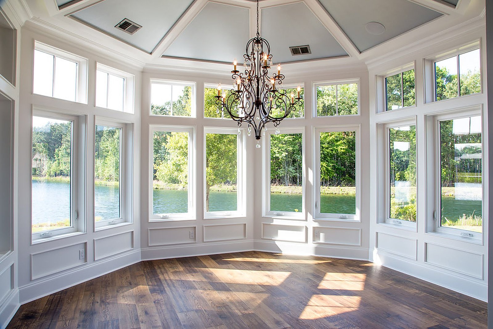 Window-wrapped dining room with a coffered ceiling overlooking the water