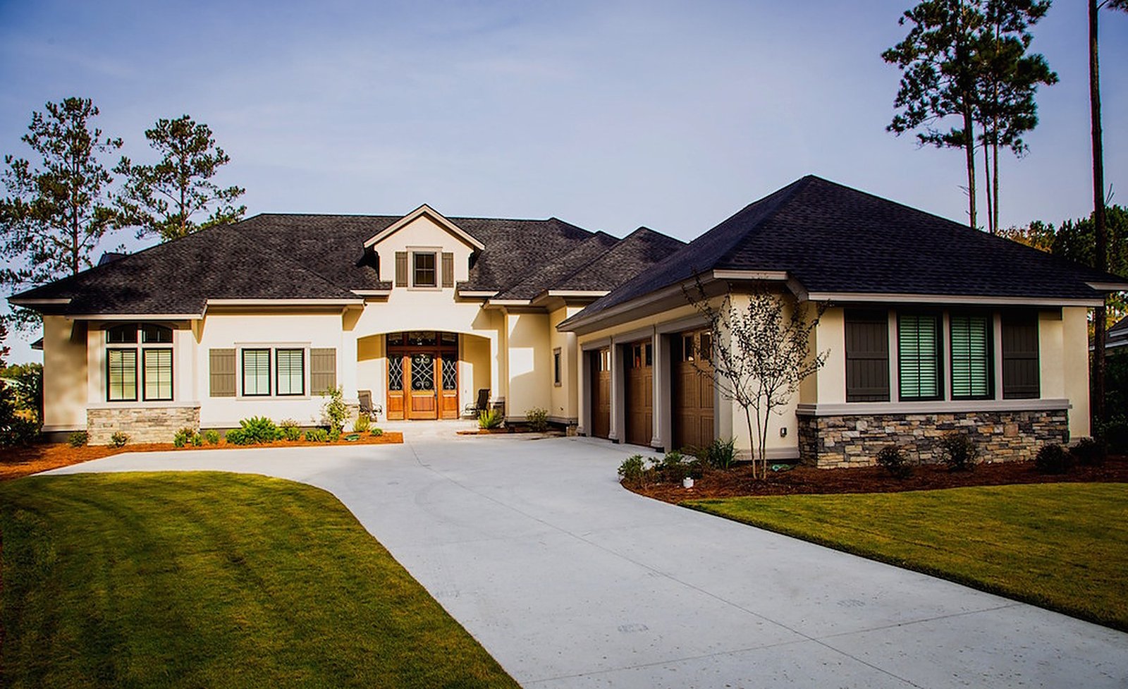 Harbor View Home front elevation at dusk with stone, stucco and a tile roof